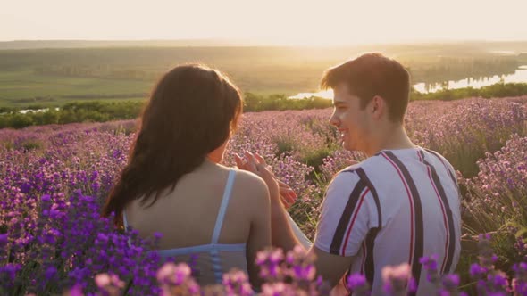 A Happy Married Young Couple in Love Sits in a Lavender Field