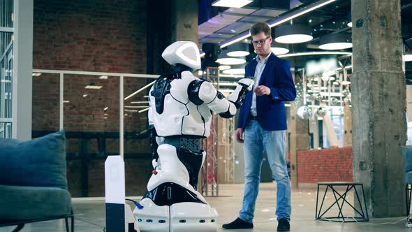 A Man in a Business Suit is Touching Robot's Hand