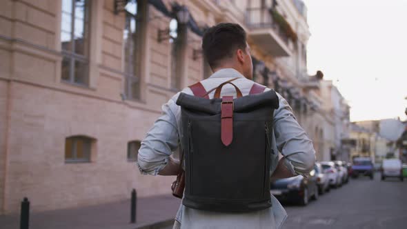 Attractive Young Handsome Man Tourist with Backpack Walking in City Center and Looking Around Slow