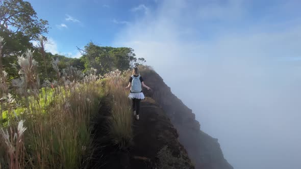 Kokee Park. Hawaii. Female Tourist with a Backpack Walks Along the Narrow Mountain Trail.