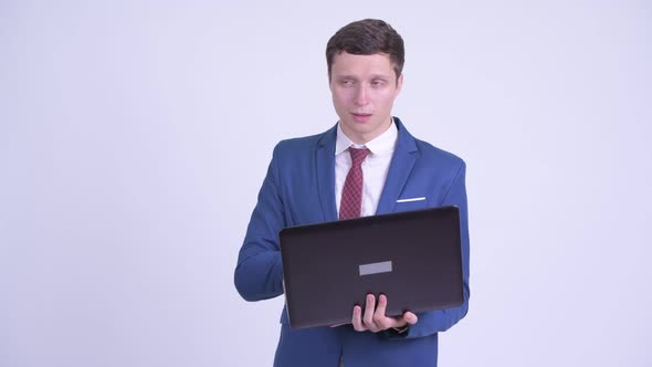 Happy Young Handsome Businessman Thinking While Using Laptop