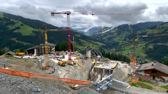 Pan aerial shot of gigantic construction site in mountains during cloudy day - Build of new modern s