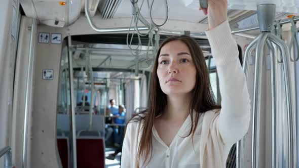 Lady Stands in Tram Holding Handrail Travelling to City