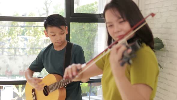Asian mother and son live at home. The couple enjoyed playing music together.