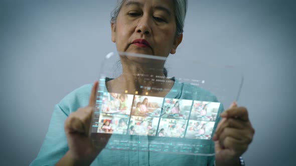 Active Senior Asian Woman Using a Futuristic Tablet 