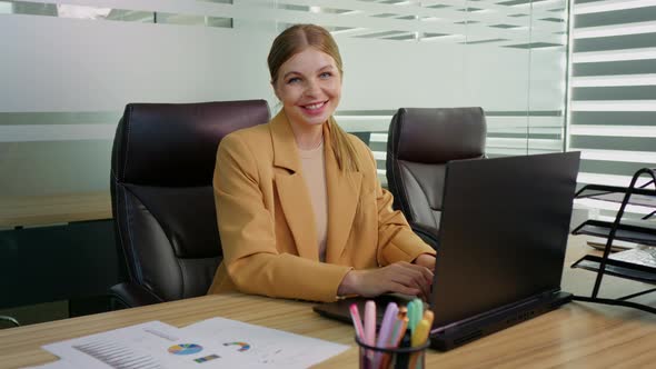 Portrait of business woman working on laptop in office.