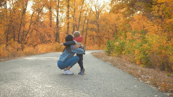 Young Mother Walking with a Little Son in Autumn Park. Happy Family in Autumn Park. Happy Family in