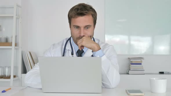 Pensive Doctor Thinking and Working on Laptop