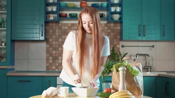 Caucasian woman at home prepares a salad of fresh vegetables tomatoes cucumbers