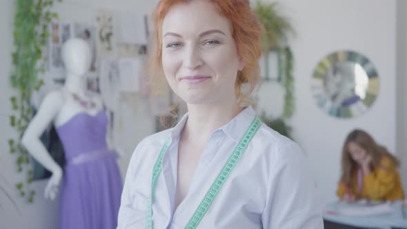 Portrait of Attractive Red-haired Seamstress Looking at Camera Smiling While Her Little Daughter