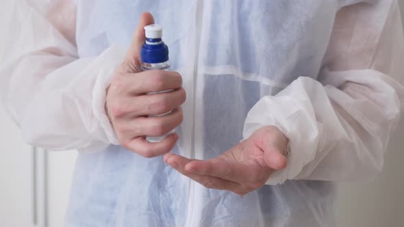 A Medical Worker in a Disposable Gown Treats His Hands with a Sanitizer Before the Operation