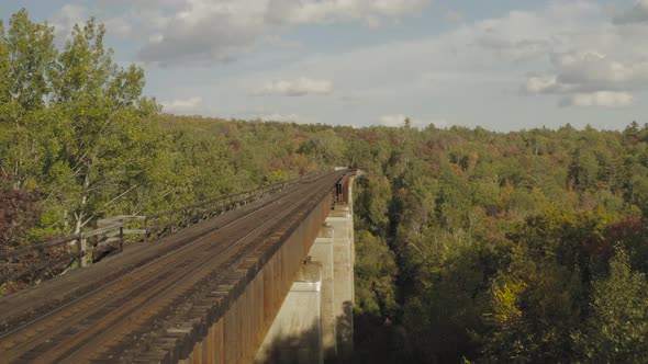 Flying through the trees along the side of a rusty railroad trestle during an early fall golden hour