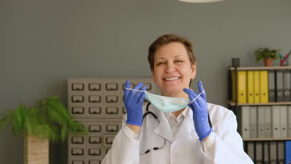 Positive Female Doctor Removes a Medical Mask in Clinic