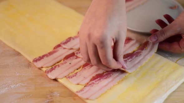 Putting smoked bacon on the sheet of raw puff pastry
