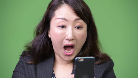 Mature Beautiful Asian Businesswoman Looking Shocked While Using Phone