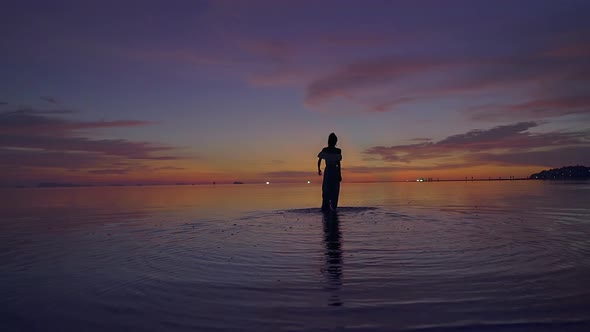 Young Woman Silhouette Walking in the Sea at Beautiful Sunset Thailand