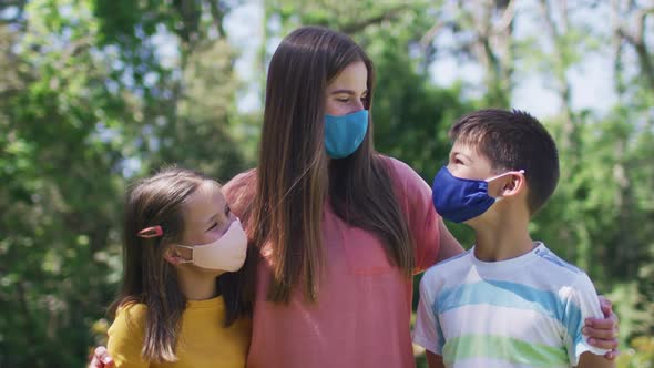 Portrait of caucasian family wearing face masks and standing together in the garden