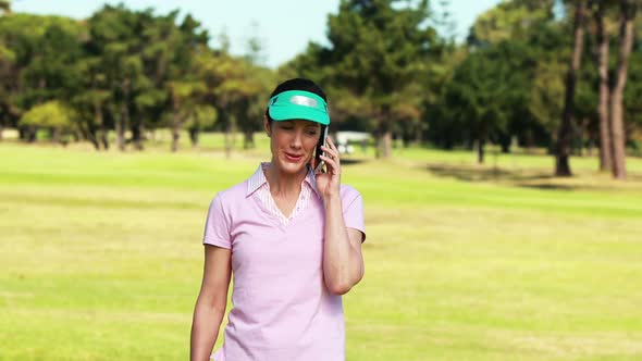 Female golf player talking on mobile phone while playing golf