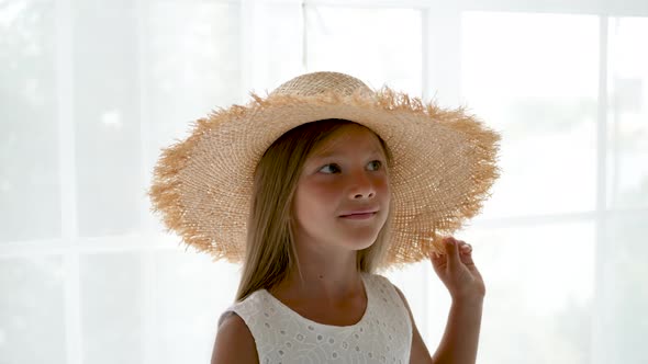 Girl in a Big Straw Hat and a White Dress Sitting