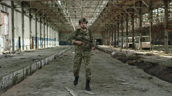 Military Soldier Patrolling Territory on Ruined Factory