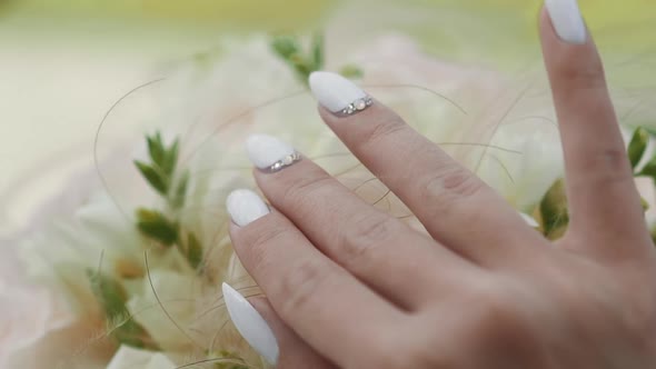 Elegant Young Bride with White Manicure Touches Bouquet