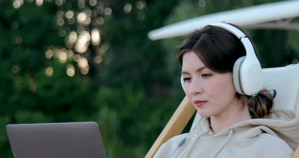 Closeup of Freelance woman in headphones working on laptop
