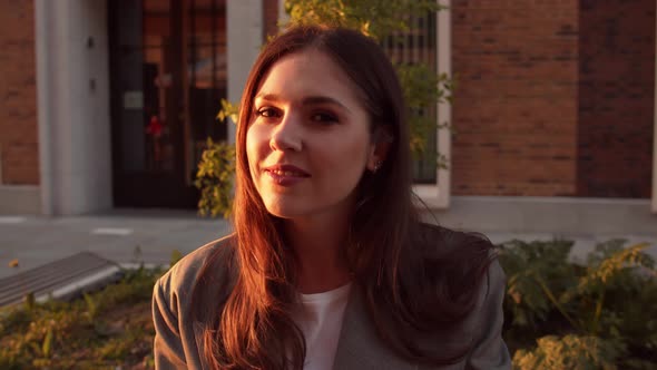 Young attractive business woman sitting outdoor on the bench. Sunset light.