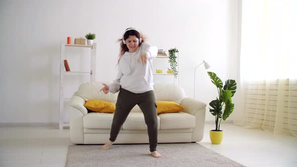 Happy Woman Listening To Music and Dancing in Living Room