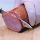 The cook cuts meat sausage into large pieces for a sandwich on a wooden table. A thick cured salami - VideoHive Item for Sale