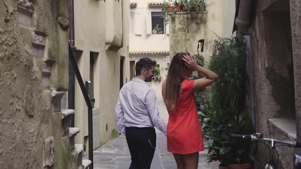 Rear view of couple walking hand in hand in alley