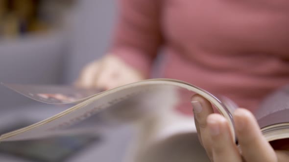 Women leading through magazines sitting on the sofa in the living room.