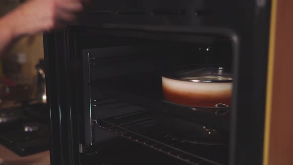 Woman Is Putting a Dish with Dough in an Electric Oven and Switching on
