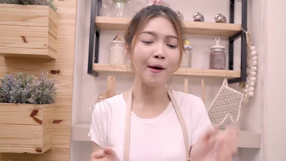 Asian blogger woman making salad in kitchen feeling happy dancing and sing a song cooking.