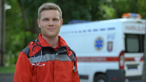 Male Paramedic Posing for Camera, Ambulance on Background, Professionalism