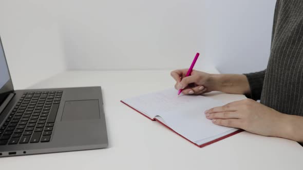 Woman Hand Writing in Notebook with Laptop