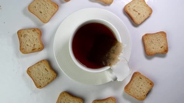 Cup of Tea with Tea Bag and a Lot of White Crispy Crackers Rotates Slowly on a Light Background