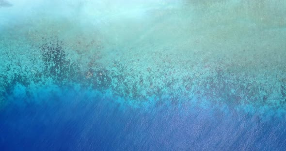 Tropical aerial tourism shot of a sandy white paradise beach and blue sea background in vibrant 4K