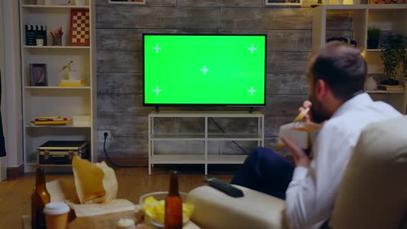 Back View of Businessman Sitting on Couch Eating Noodles