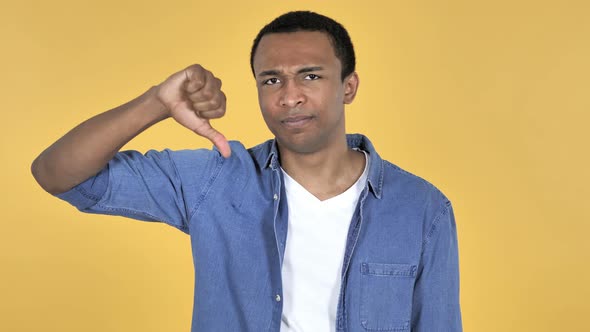 Young African Man Gesturing Thumbs Down, Yellow Background