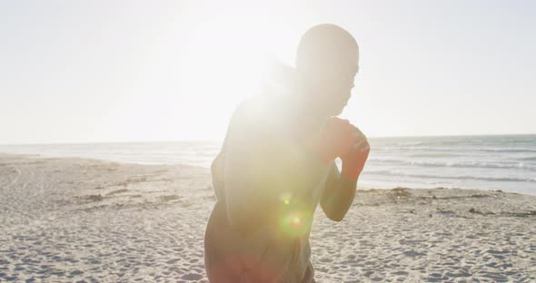 Focused african american man boxing, exercising outdoors by the sea