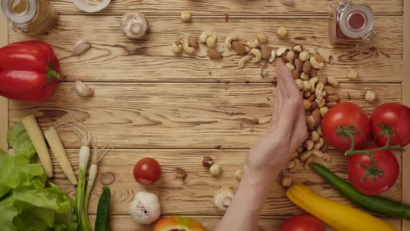 Faceless Person Moving Nuts on Wooden Table. Healthy Food.