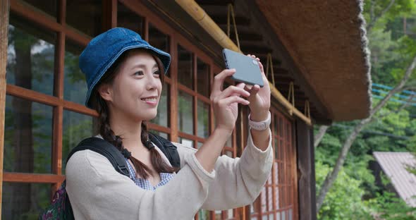 Woman use of mobile phone to take photo in Japanese wooden house 