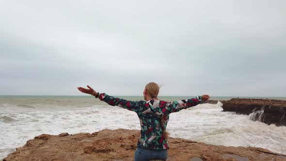 Beautiful Girl on the Ocean in Storm. Girl Looks Into the Distance at the Sea. Sea Waves Are