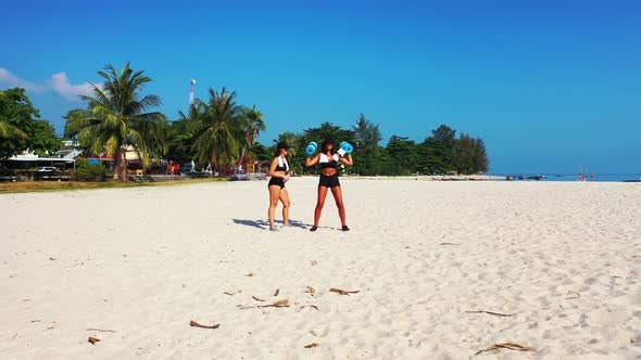 Pretty smiling ladies relaxing having fun on the beach on summer white sand and blue 4K background