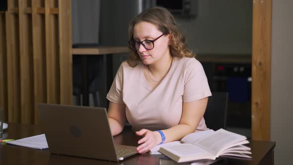 Woman with Glasses is Sitting at Desk and Working at Home Communicating with Colleagues and Friends