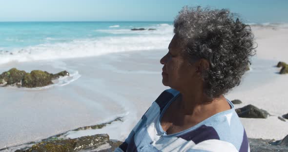 Senior woman sitting on a rock at the beach