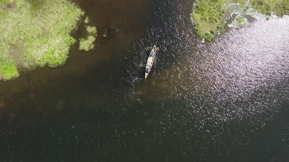 Drone shot of a canoe paddling into a small channel with sunlight reflections