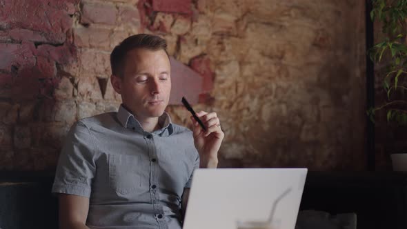 Thoughtful Serious Young Man Student Writer Sit at Home Office Desk with Laptop Thinking of