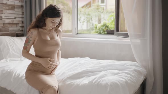 Happy Pregnant Woman Stroking Belly Near Window Indoors