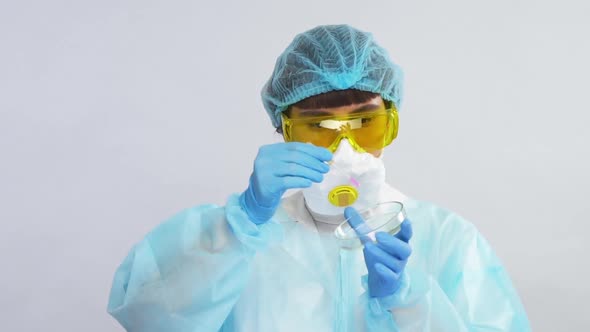 Young Female Scientist Pouring Pink Liquid From Pipette on Petri Dish Wearing Protection Suit